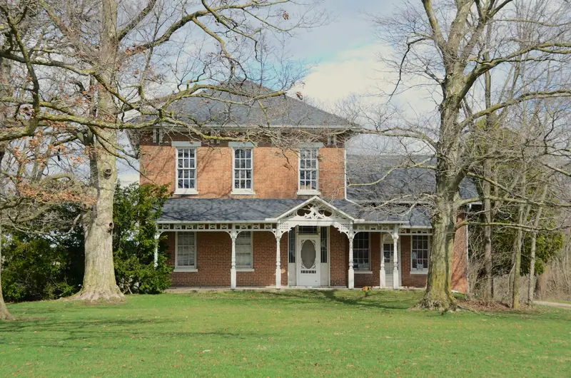Two-story red brick house with a covered front porch and bare trees